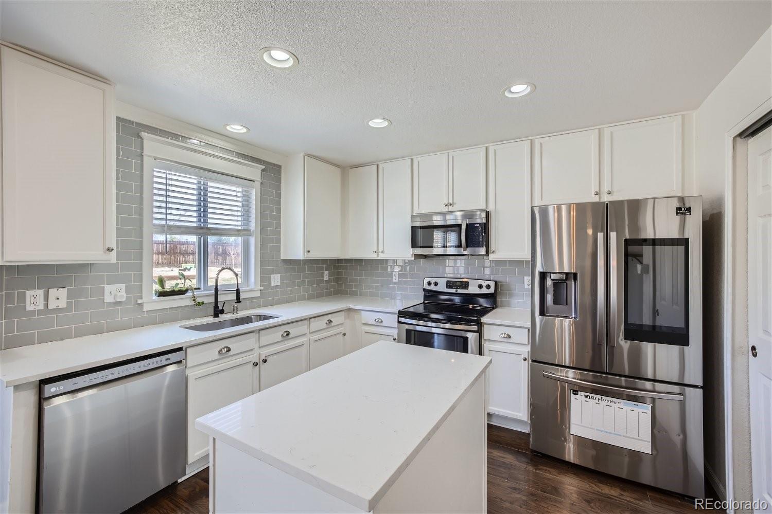 6632 Balance Circle Colorado Springs, CO 80923 - Photo 9 of 28 a kitchen with white cabinets and stainless steel appliances