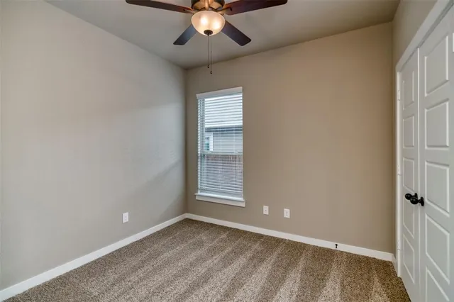 an empty room with a window and a ceiling fan