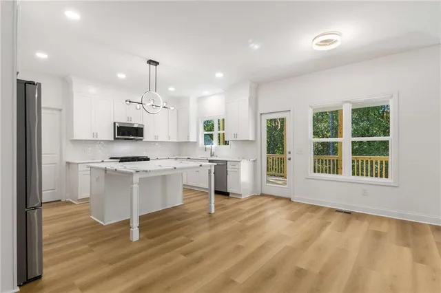 an empty room with windows and kitchen view