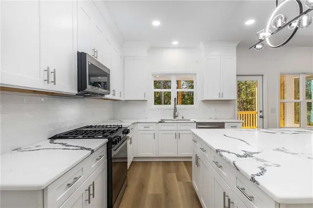 a kitchen with granite countertop a sink a stove top oven and white cabinets