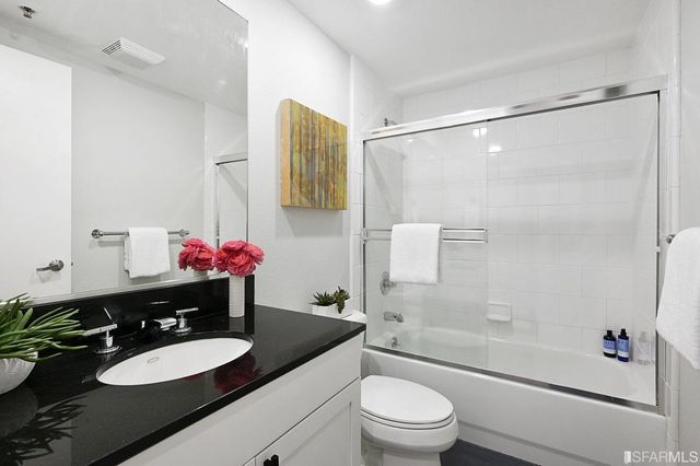 a bathroom with a granite countertop sink toilet mirror and shower