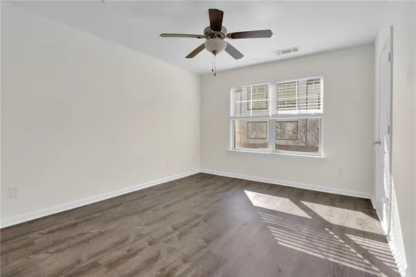 a view of an empty room with a window and wooden floor