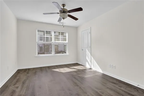 an empty room with wooden floor fan and windows