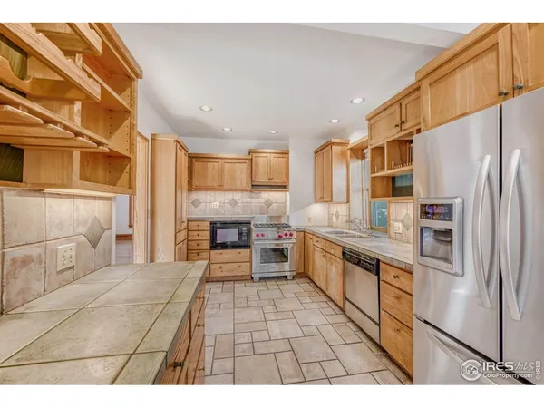 a kitchen with granite countertop a refrigerator and a stove top oven