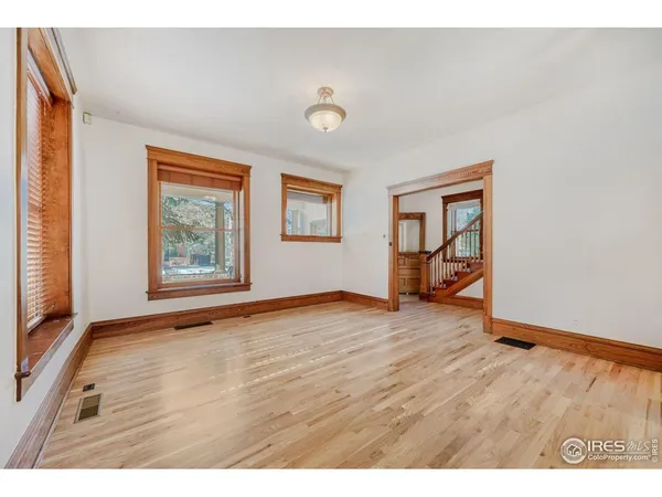 a view of an empty room with a window and wooden floor