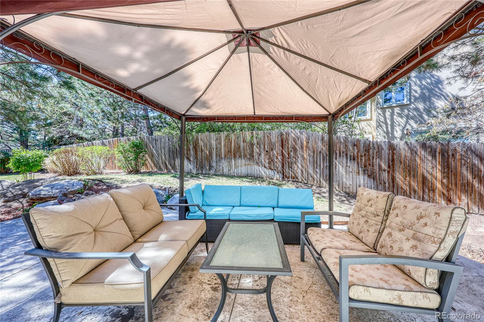 7963 Glen Ridge Drive Castle Pines, CO 80108 - Photo 39 of 48 a backyard of a house with sofas table and chairs