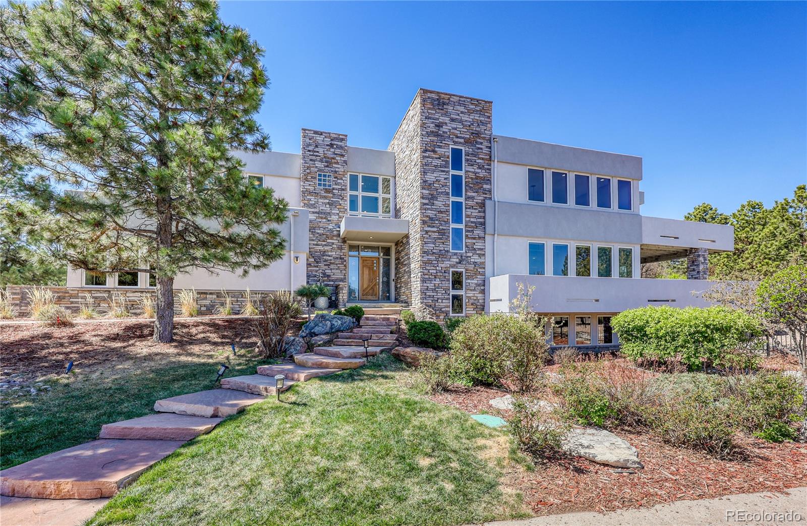 7963 Glen Ridge Drive Castle Pines, CO 80108 - Photo 7 of 48 a front view of a building with garden and trees