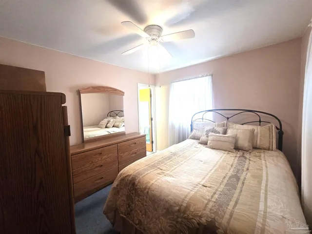 a bedroom with a large bed and a chandelier fan