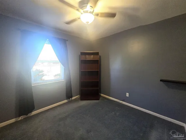 an empty room with windows and chandelier fan