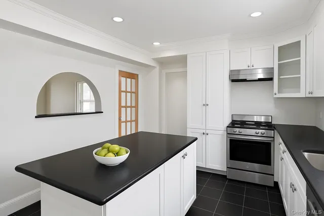 a kitchen with stainless steel appliances a stove a microwave a sink a refrigerator and white cabinets