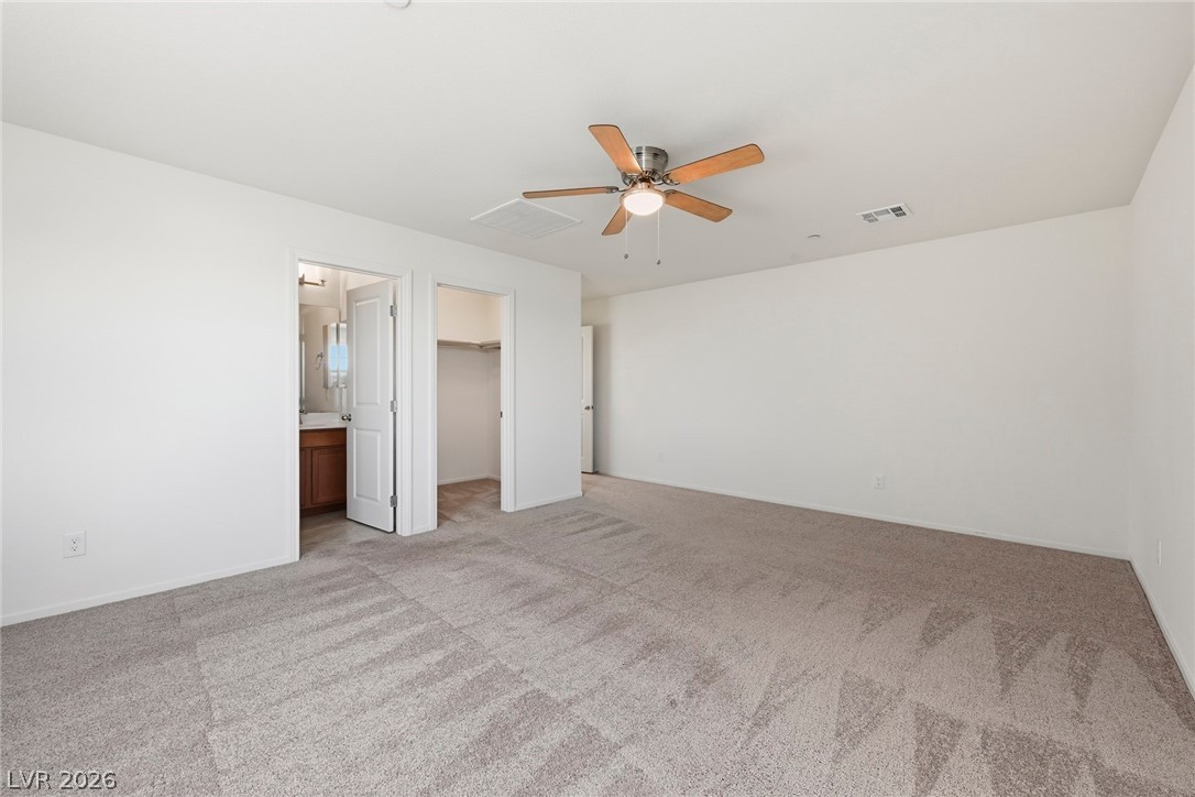 250 Dedication Avenue Henderson, NV 89011 - Photo 32 of 67 Unfurnished bedroom featuring a walk in closet, light carpet, ceiling fan, and connected bathroom