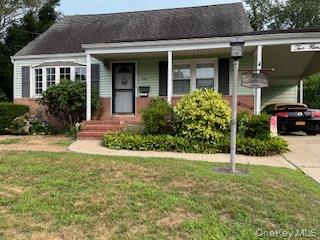 View of front of home featuring a carport, concrete driveway, a front yard, and covered porch