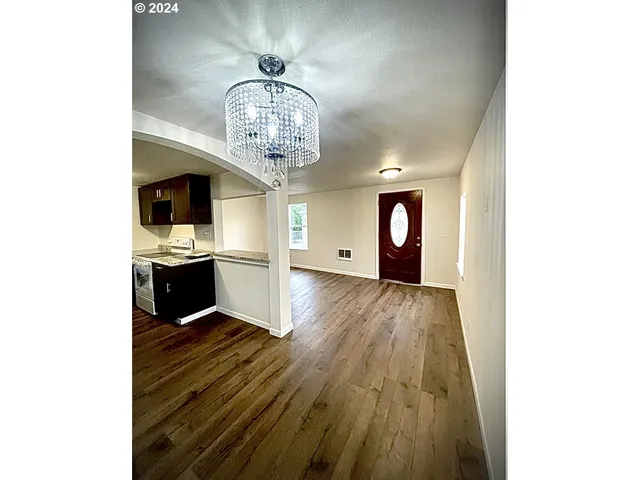 a view of a room with wooden floor chandelier and kitchen