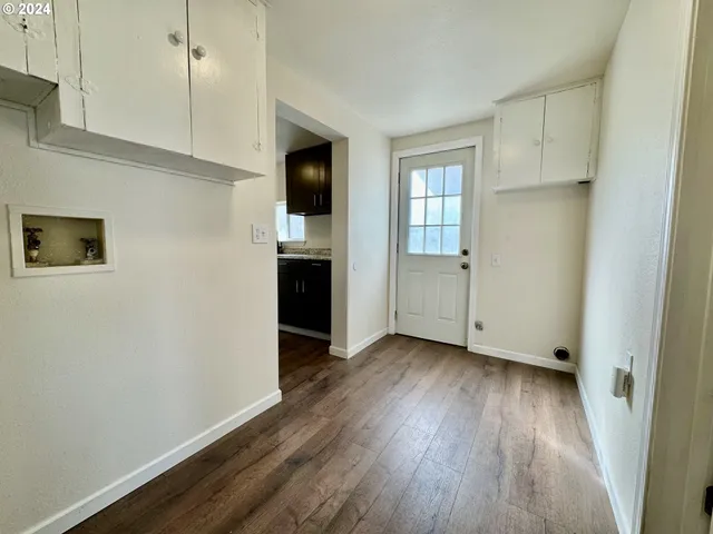 a view of empty room with wooden floor and window