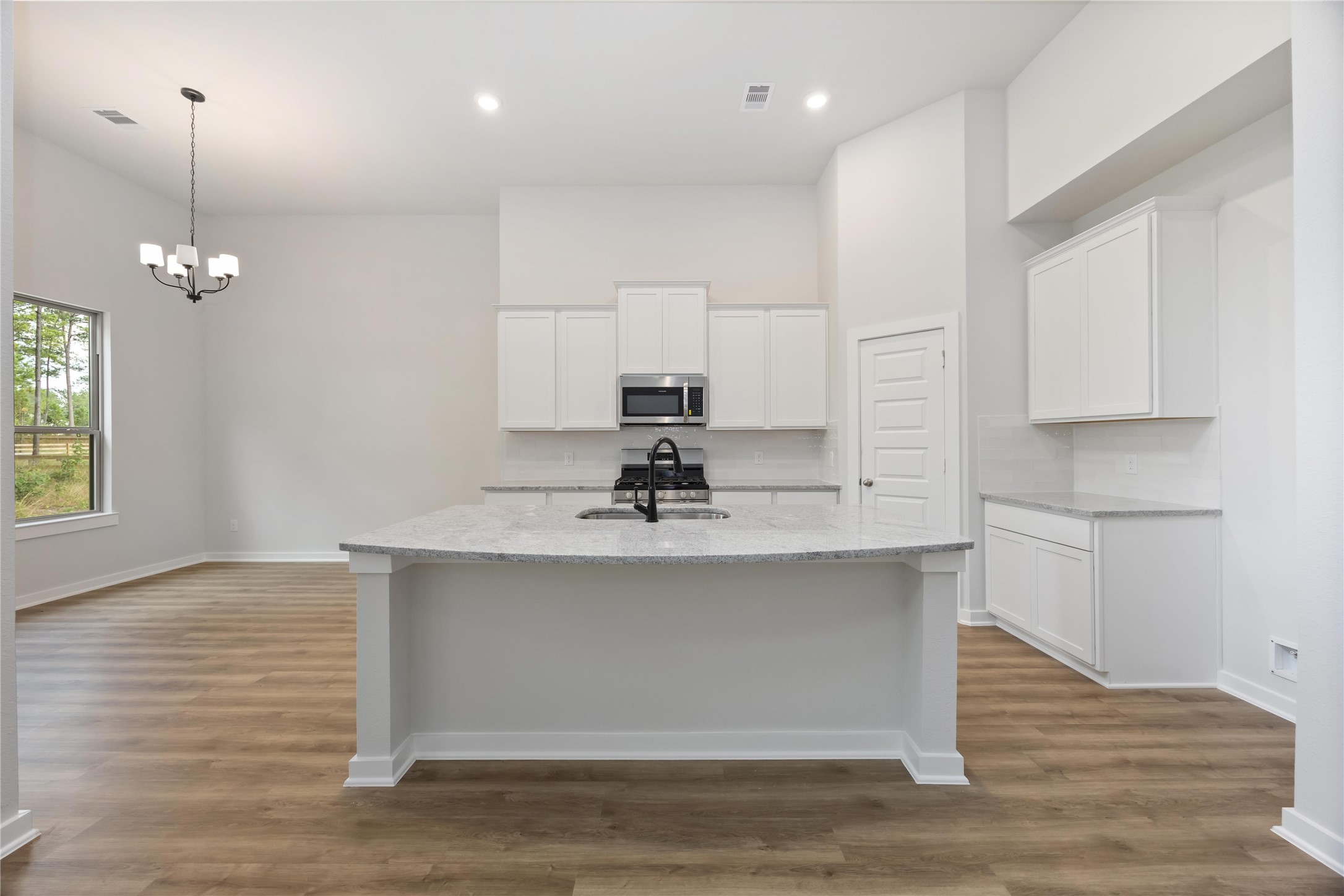 13511 Caldwell Street Conroe, TX 77303 - Photo 7 of 29 a view of a kitchen with kitchen island a sink wooden floor and living room view