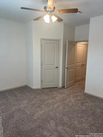 an empty room with closet and a chandelier fan