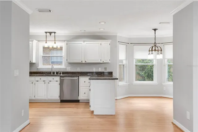 a kitchen with stainless steel appliances granite countertop a stove a sink and a granite counter tops with white cabinets next to a window