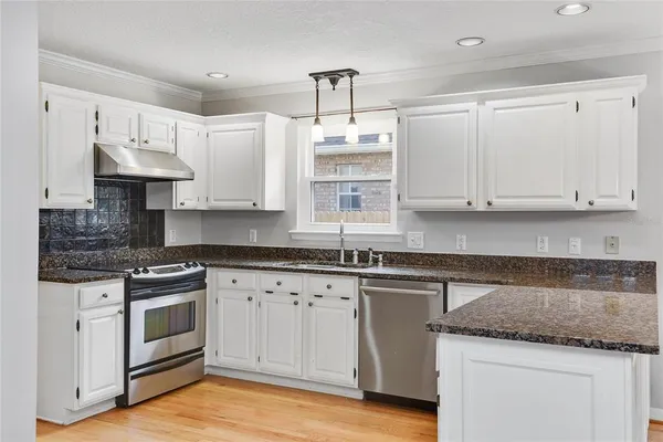 a kitchen with stainless steel appliances granite countertop a sink and cabinets with wooden floor
