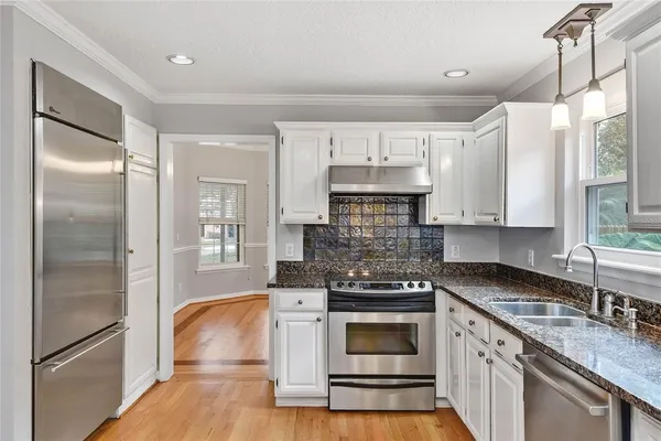 a kitchen with kitchen island granite countertop a sink cabinets and stainless steel appliances