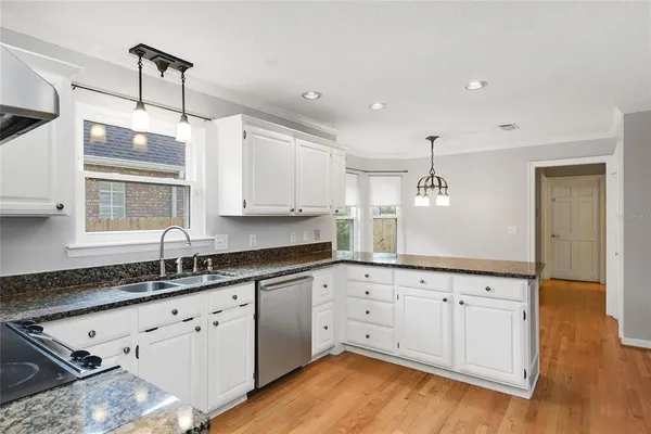 a kitchen with granite countertop white cabinets white appliances and sink