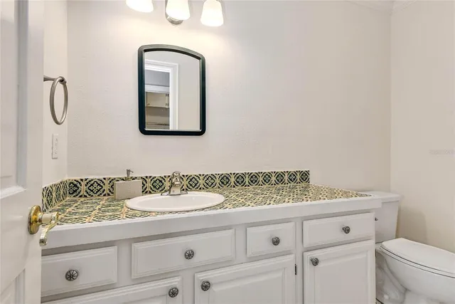 a bathroom with a granite countertop toilet sink and mirror
