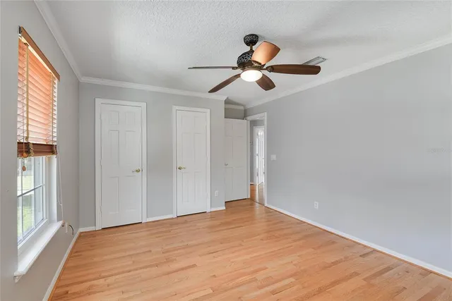 a view of empty room with wooden floor and fan