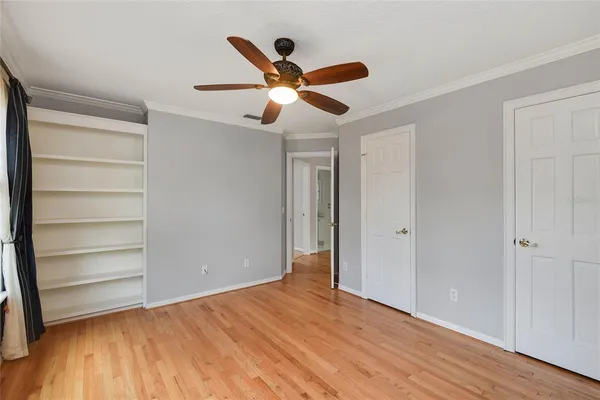 a view of empty room with wooden floor and ceiling fan