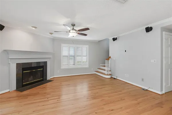 a view of an empty room with wooden floor fireplace and a window