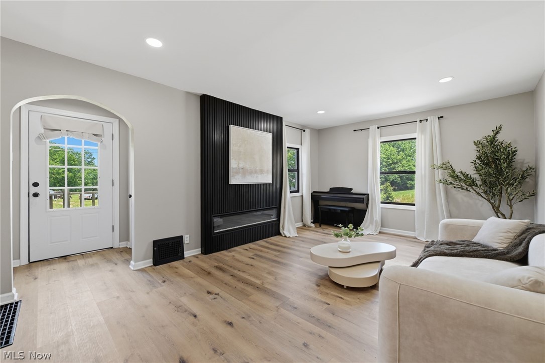 951 Bey Road Akron, OH 44312 - Photo 6 of 34 Spacious living area featuring light wood-finish flooring, a modern black paneled fireplace, recessed lighting, and multiple windows