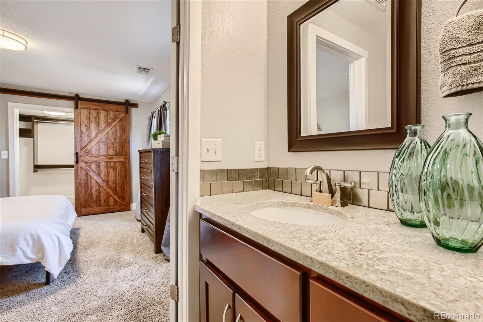 2310 South Decatur Street Denver, CO 80219 - Photo 15 of 27 a en suite bathroom with a granite countertop sink and a mirror