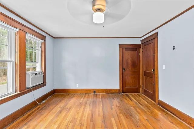 a view of an empty room with wooden floor and window