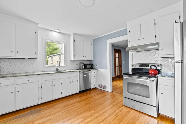 a kitchen with granite countertop a stove a sink and a refrigerator