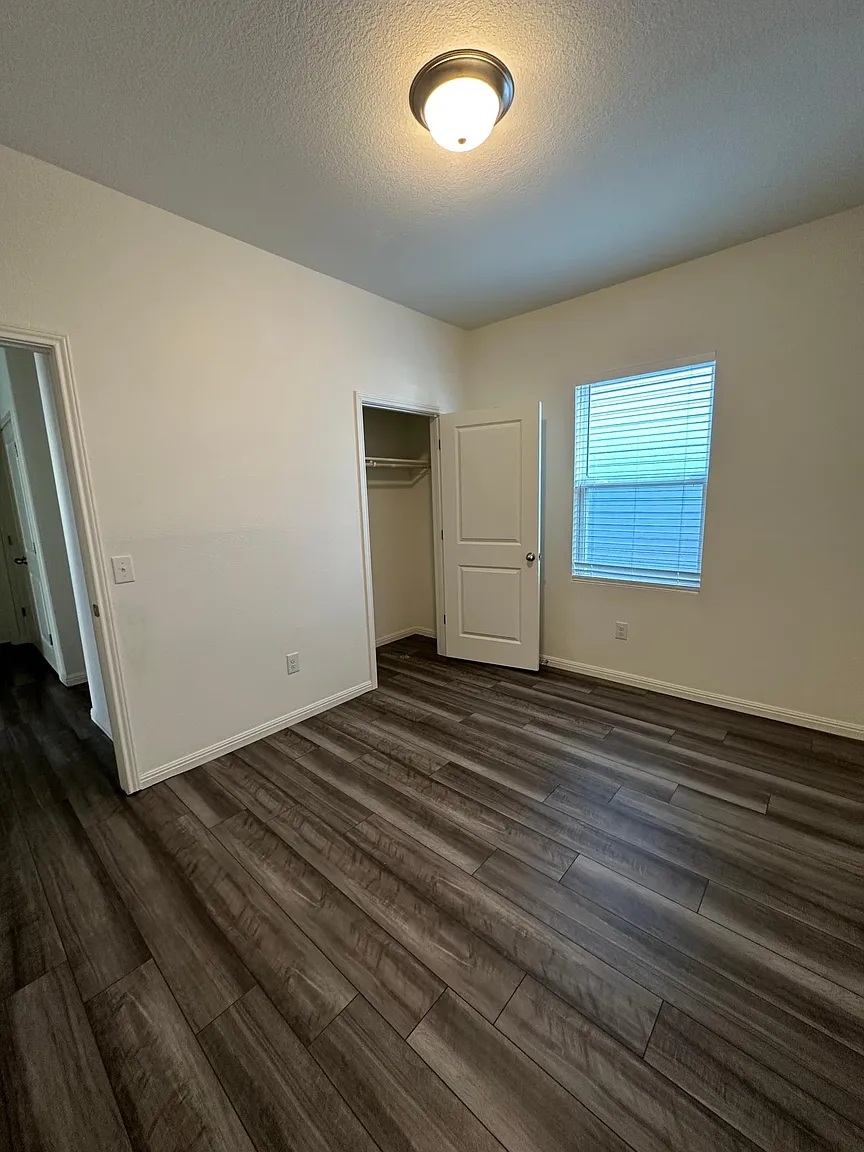 114 Aoudad Road Hutto, TX 78634 - Photo 9 of 22 Unfurnished bedroom featuring a textured ceiling, dark wood-style flooring, and a closet