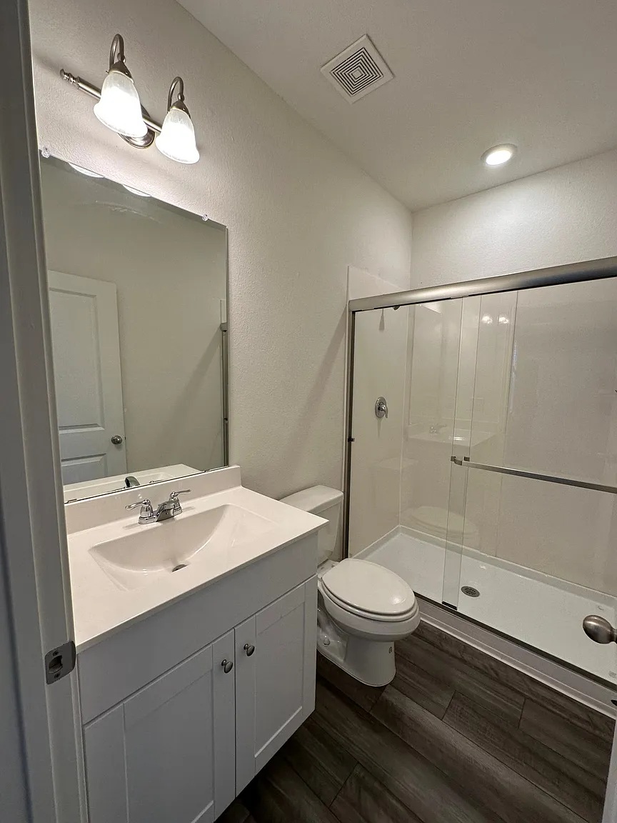 114 Aoudad Road Hutto, TX 78634 - Photo 15 of 22 Full bathroom featuring vanity, a shower stall, and dark wood-style floors