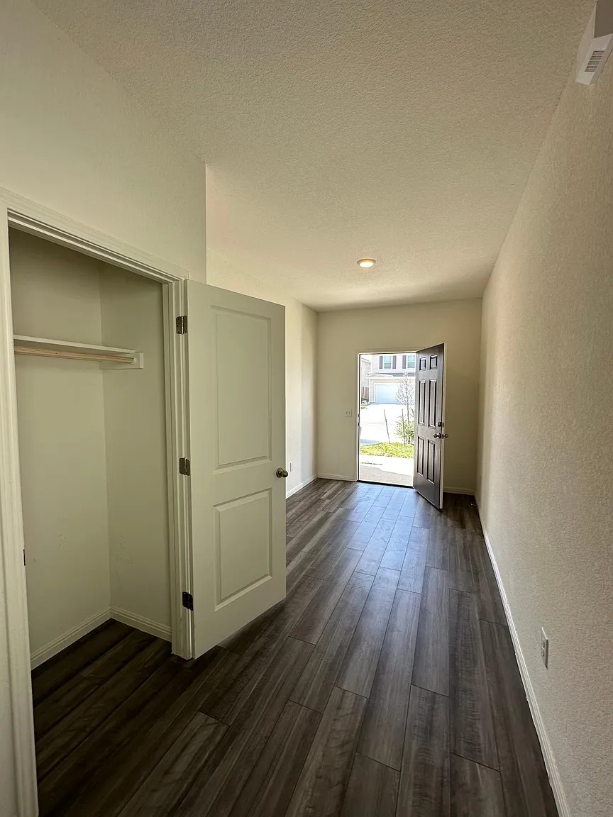 114 Aoudad Road Hutto, TX 78634 - Photo 2 of 22 Unfurnished bedroom with dark wood-type flooring, access to outside, a textured ceiling, and a closet