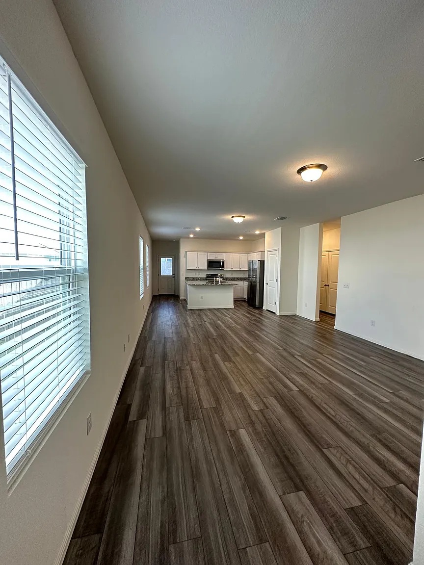 114 Aoudad Road Hutto, TX 78634 - Photo 3 of 22 Unfurnished living room with dark wood-style flooring and baseboards