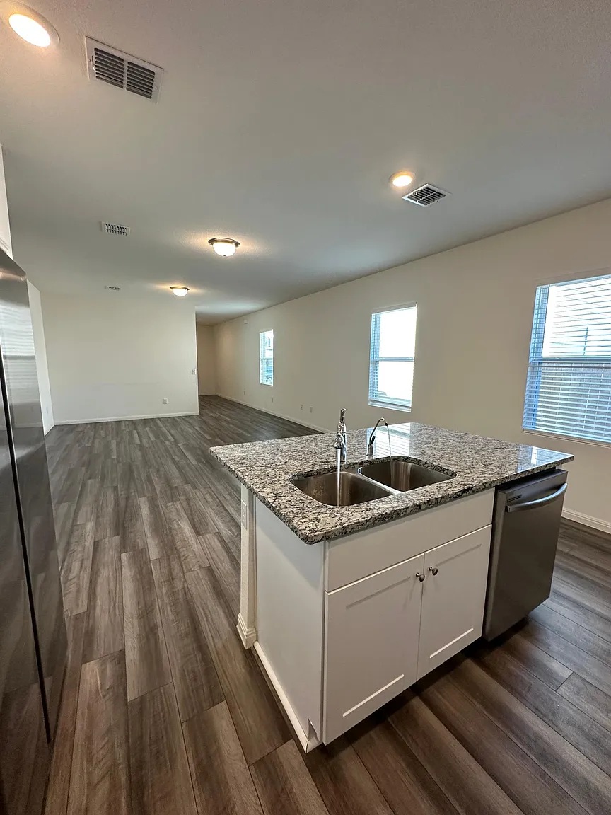 114 Aoudad Road Hutto, TX 78634 - Photo 22 of 22 Kitchen with light stone countertops, white cabinetry, a center island with sink, dark wood-type flooring, and open floor plan