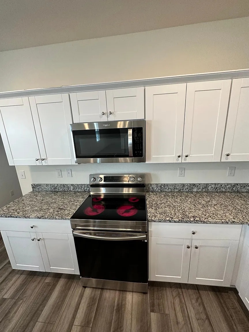 114 Aoudad Road Hutto, TX 78634 - Photo 5 of 22 Kitchen with stainless steel appliances, white cabinetry, and dark wood-style floors
