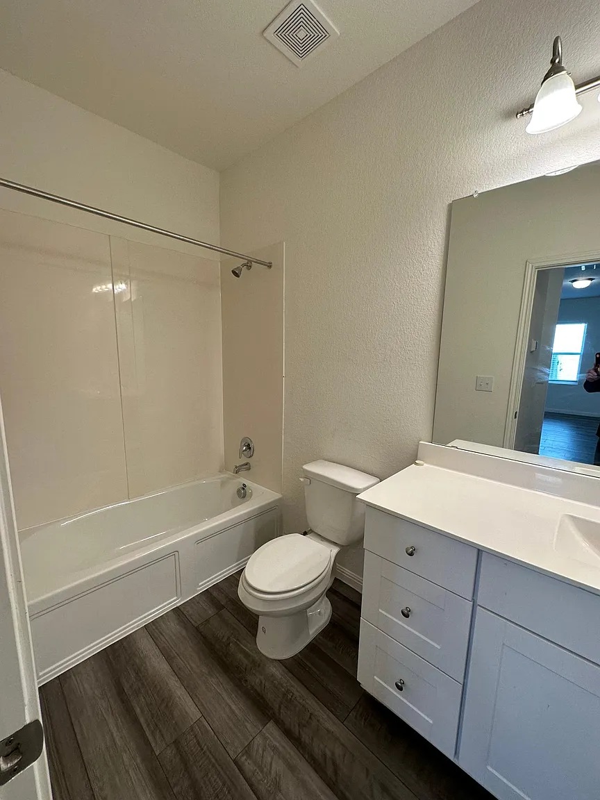 114 Aoudad Road Hutto, TX 78634 - Photo 7 of 22 Bathroom with dark wood-style floors, vanity, a textured wall, and shower / washtub combination