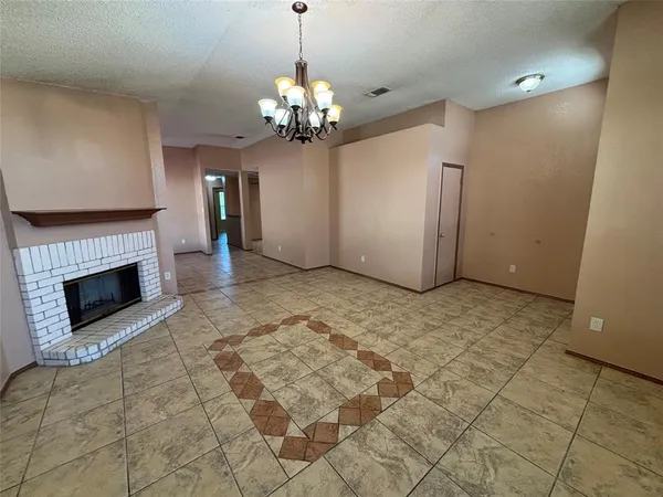 a view of a livingroom with a fireplace a chandelier and windows