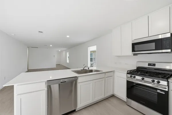 a kitchen with stainless steel appliances a sink dishwasher stove and microwave with wooden cabinets