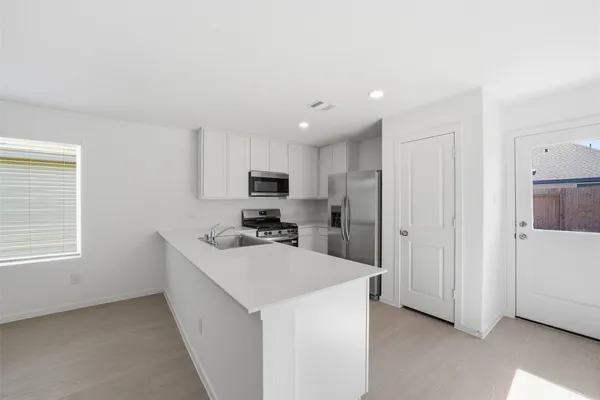 a kitchen with stainless steel appliances a sink a stove a refrigerator cabinets and a window