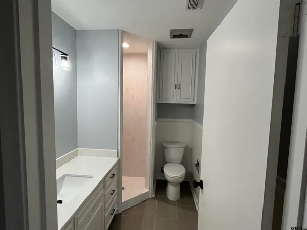 a bathroom with a granite countertop sink a toilet and vanity