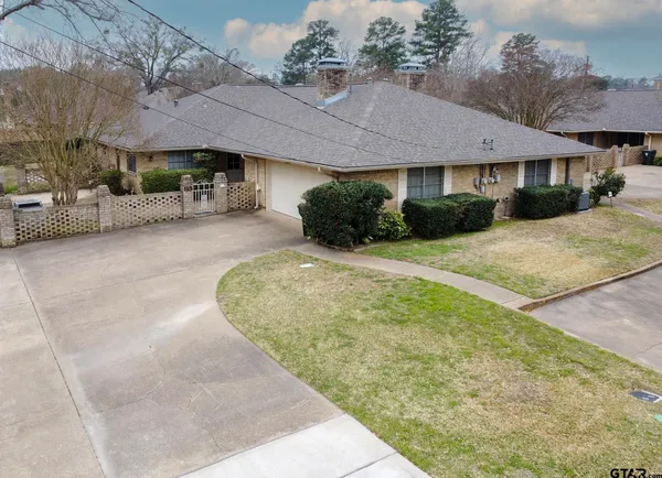 a view of a white house with a yard plants and large tree