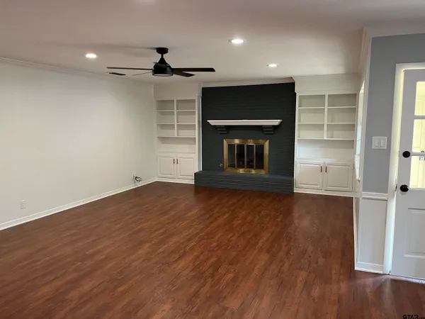 an empty room with wooden floor a fireplace and entryway