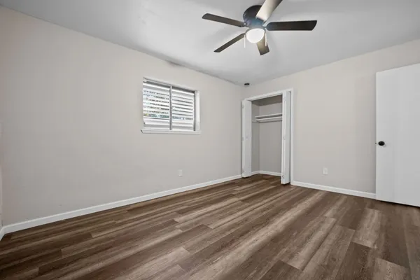 a view of empty room with wooden floor and fan
