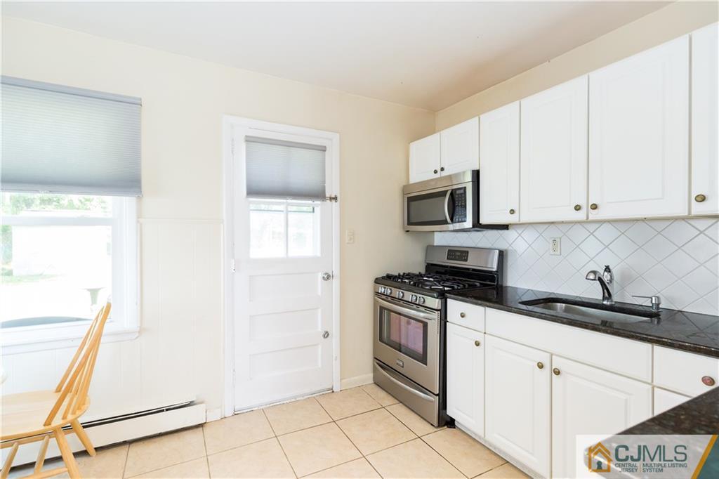 5 Mercury Road Edison, NJ 08817 - Photo 10 of 29 a kitchen with granite countertop white cabinets and black appliances