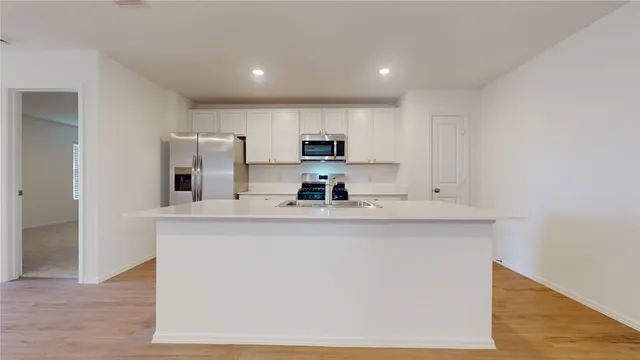 a kitchen with kitchen island a sink a stove a refrigerator and white cabinets