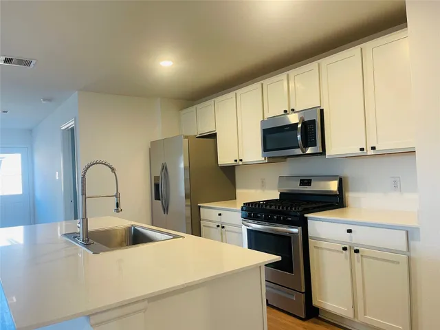 a kitchen with stainless steel appliances a stove microwave sink and refrigerator
