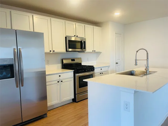 a kitchen with stainless steel appliances a refrigerator sink and microwave
